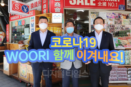 손태승(오른쪽) 우리금융그룹 회장과 권광석(왼쪽) 우리은행장이 서울 중구 소재 남대문시장에서 물품구매 후 박칠복 남대문시장 남산상회 대표와 코로나19 극복을 다짐하며 기념촬영을 하고 있다.  우리금융 제공